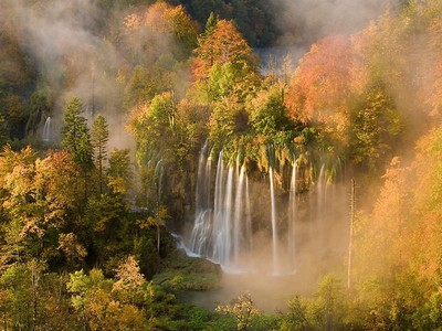 Autumn colours on the trees surrounded by the early fog, Veliki Prstvaci waterfalls, close to Gradinsko lake, Upper Lakes, Plitvice National Park, Croatia.